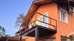 A two-story house with a wooden deck, large windows, and a balcony.