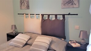 A neatly made bed with striped pillows, a black headboard, and a wall-mounted curtain.