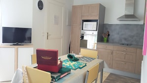 A compact living space with a dining area, a kitchenette, and a television.