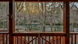 A wooden deck with a view of a river and trees.