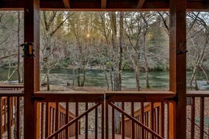 A wooden deck with a view of a river and trees.