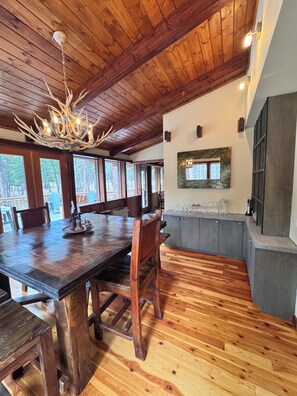 A wooden dining area with a large table, chairs, and a ceiling with exposed beams.