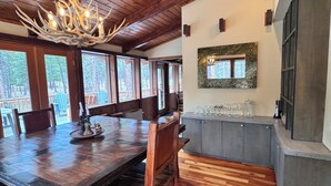 A wooden dining area with a large table, chairs, and a chandelier. - Home in the Bitterroots (Victor)