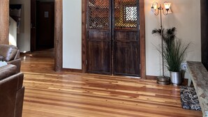 A spacious room with wooden floors, a large wooden door with intricate lattice design, and a ceiling with exposed beams. - Home in the Bitterroots (Victor)