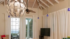 A dining area with a round table, yellow chairs, a ceiling fan, and a modern chandelier. - Seagrape 2 - 1 bedroom suite at Seagrape Vista (Cruz Bay)