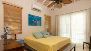 A bedroom with a bed, a ceiling fan, a window with blinds, an air conditioner, and a wall-mounted picture. - Seagrape 2 - 1 bedroom suite at Seagrape Vista (Cruz Bay)