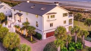 A large, two-story house with a flat roof and multiple windows, surrounded by lush greenery and a beach view. - Discounts!! Serenity- 2 50th One of a kind Oceanfront Master Piece, Pool/Hot Tub (Isle Of Palms)