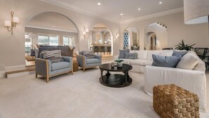 A spacious living room with a sofa, armchairs, and a coffee table. There are arched doorways leading to other rooms. - Discounts!! Serenity- 2 50th One of a kind Oceanfront Master Piece, Pool/Hot Tub (Isle Of Palms)