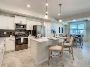 A modern kitchen with a central island, stainless steel appliances, and pendant lighting.