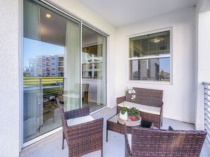 Ein Balkon mit Korbmöbeln, einem Tisch und einem Blumentopf.
