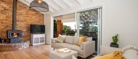 A living room with a brick fireplace, a television, and a sofa with cushions.