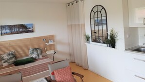 A modern living room with a sofa, a dining table, and a window with curtains.