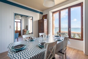 Enjoy meals with a view from this dining area featuring a large table for six and a coastal view through large windows.