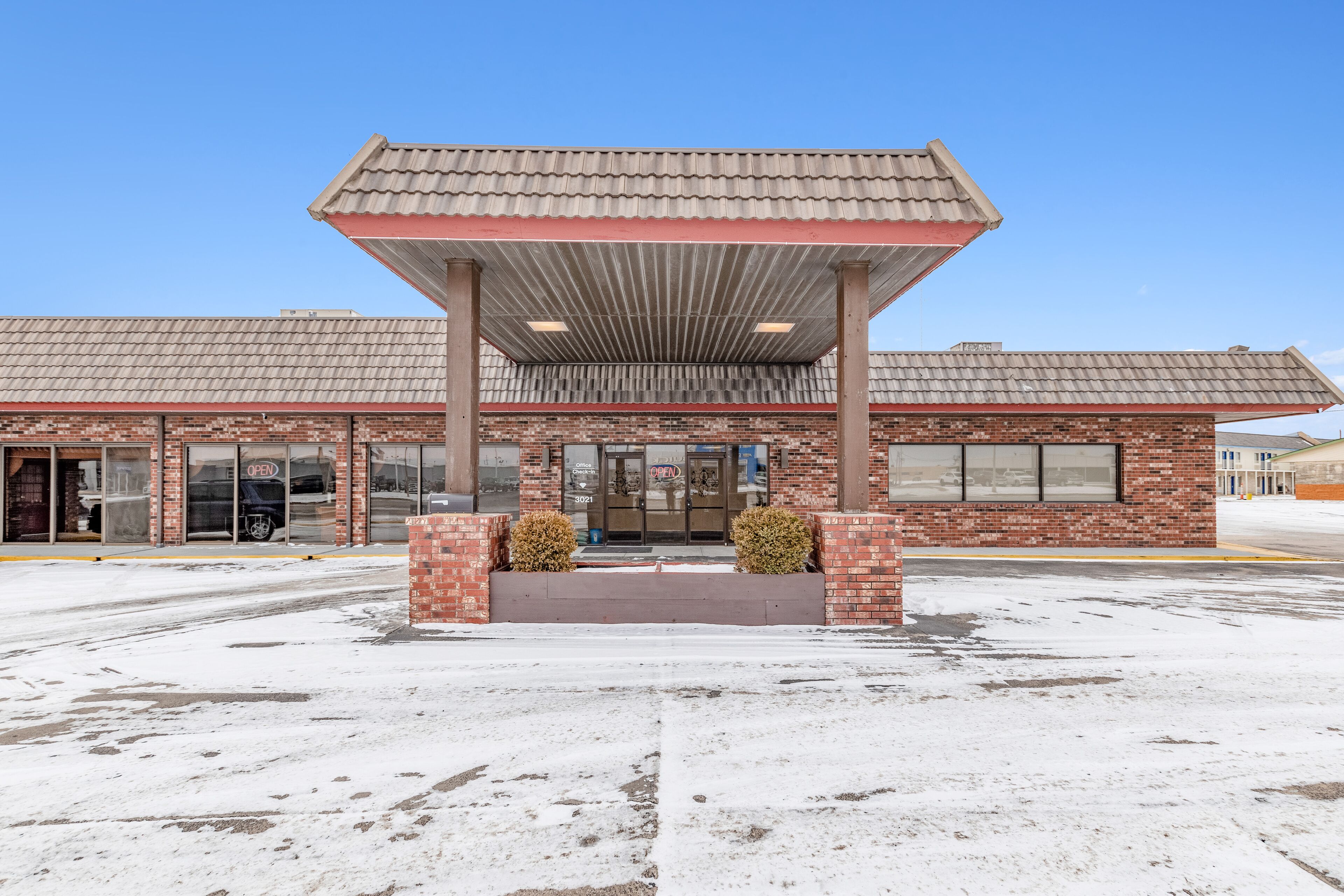 A building with a covered entrance, brick facade, and large windows.