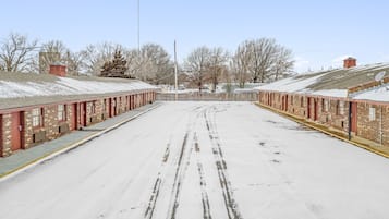 A snow-covered street with a row of brick buildings on either side, featuring a clear sky.