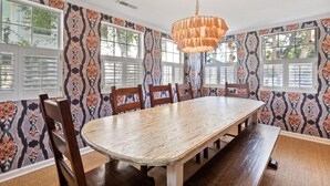 A dining room with a large wooden table, six chairs, and a chandelier.