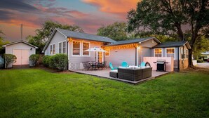 A two-story house with a covered patio area, a barbecue grill, and a small shed.