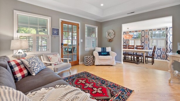 A spacious living room with a grey couch, patterned rugs, and a dining area with a table and chairs.