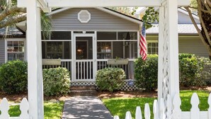 A house with a front porch, a pathway leading to the entrance, and a white picket fence.