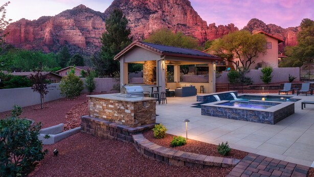 A backyard with a barbecue area, a hot tub, and a pool.