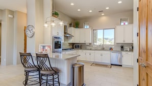A modern kitchen with white cabinets, stainless steel appliances, and a central island.