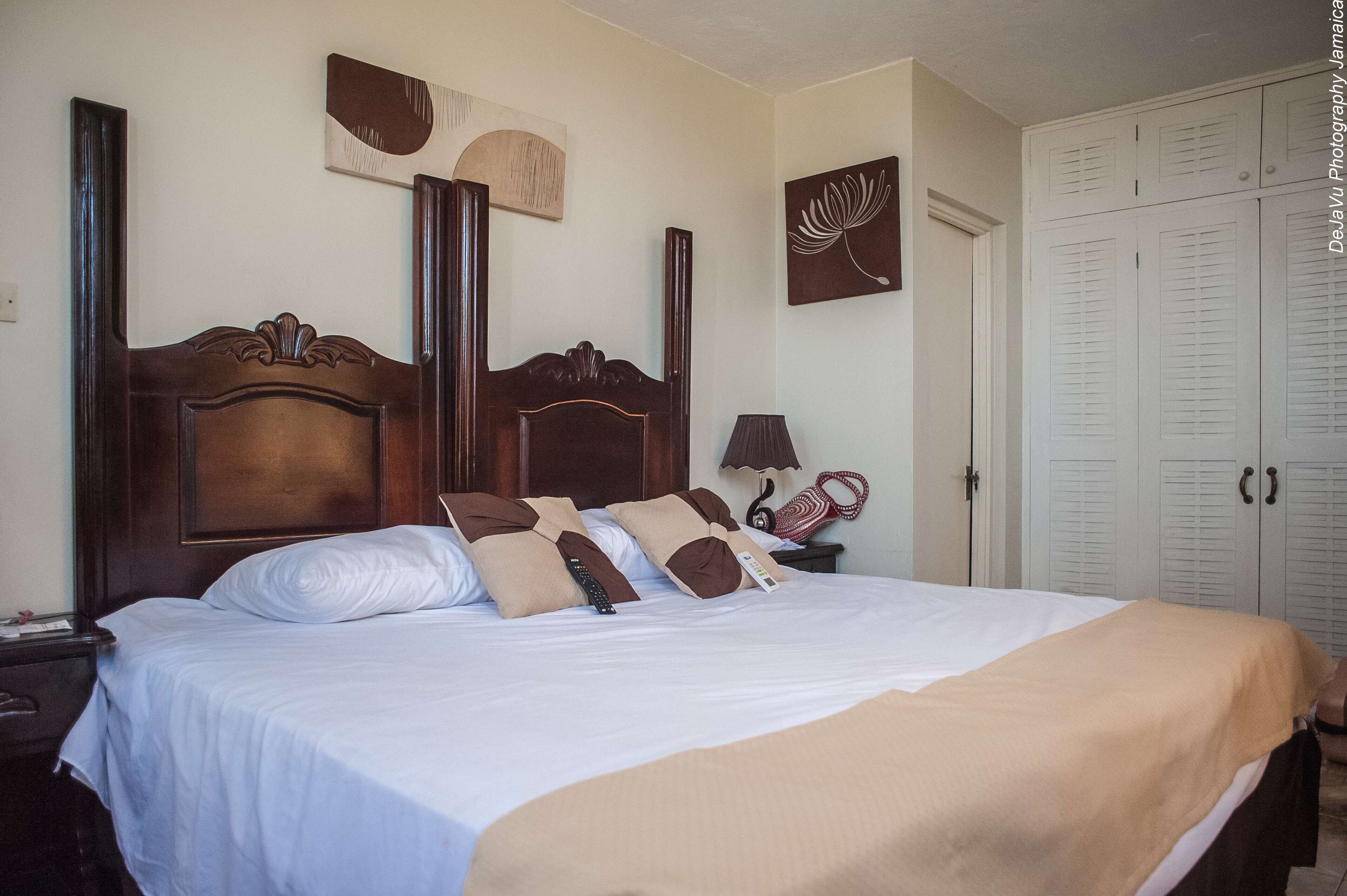 A neatly made bed with a wooden headboard, a bedside lamp, and a wall-mounted artwork.