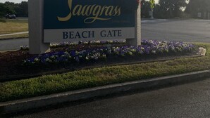 A sign for Sawgrass Beach Gate with a clear sky and clouds in the background.