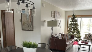Een moderne woonkamer met een eethoek, met een ronde tafel met stoelen, een bank, een salontafel en een kerstboom.