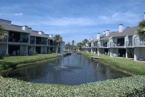 Un canal recorre un complejo turístico con edificios de varios pisos, cada uno con balcones y áreas de estar al aire libre.