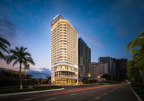 A high-rise hotel with multiple balconies, a well-lit entrance, and a modern architectural design.