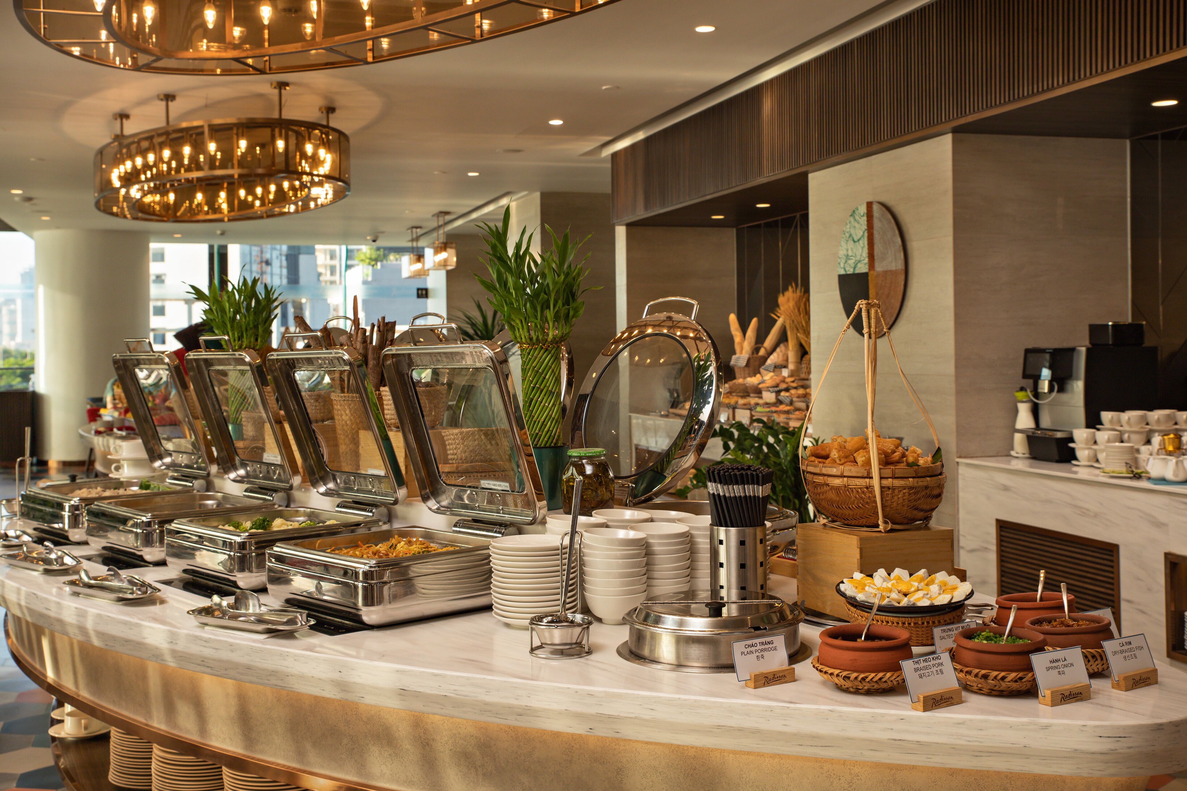 A buffet setup with various food stations, including a fruit bowl, a bread basket, and multiple serving dishes.