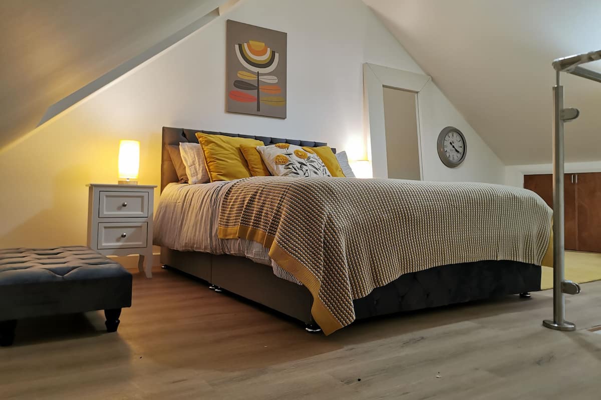 A bedroom with a bed, bedside tables, a lamp, a clock, and a ceiling light.