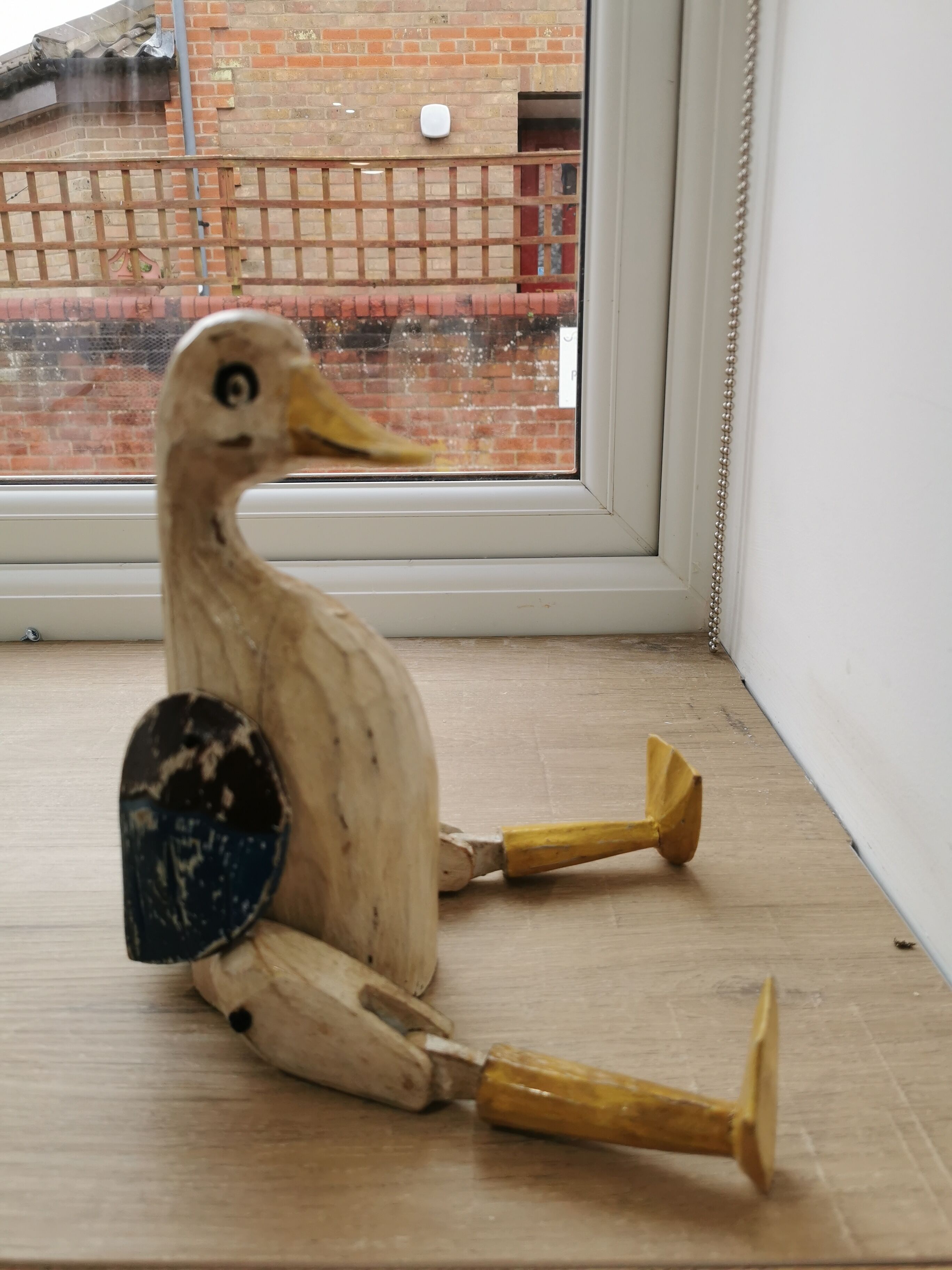 A duck-shaped sculpture with a brick wall and window in the background.