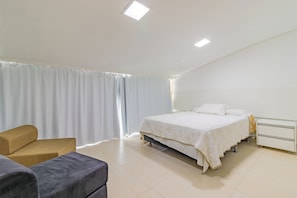 A bedroom with a bed, a nightstand, a chair, and a desk.