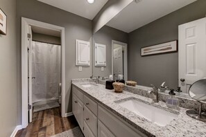 A bathroom with a double sink vanity, a large mirror, and a shower curtain.