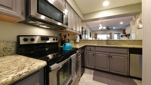 A kitchen with granite countertops, stainless steel appliances, and a built-in microwave. - Comal River Getaway at the Froh Haus C206 (New Braunfels)