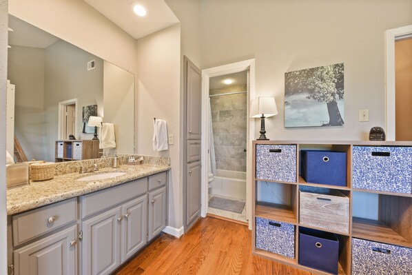 A bathroom with a double sink, vanity, and storage shelves. - Comal River Getaway at the Froh Haus C206 (New Braunfels)