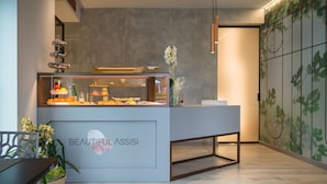 A reception desk with a glass display case, a potted plant, and a sign that reads "Beautiful Assisi Suite." - Beautiful Assisi Suite (Assisi)