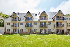 A multi-story residential building with balconies, a flat roof, and a well-maintained lawn. - Residence Le Domaine de la Corniche - Vacanceole (Auberville)