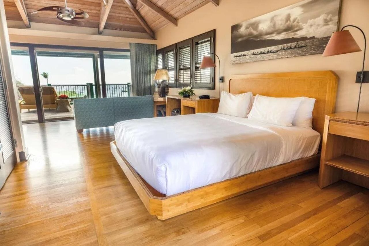 A spacious bedroom with a large bed, wooden headboard, and a view of the outdoors.