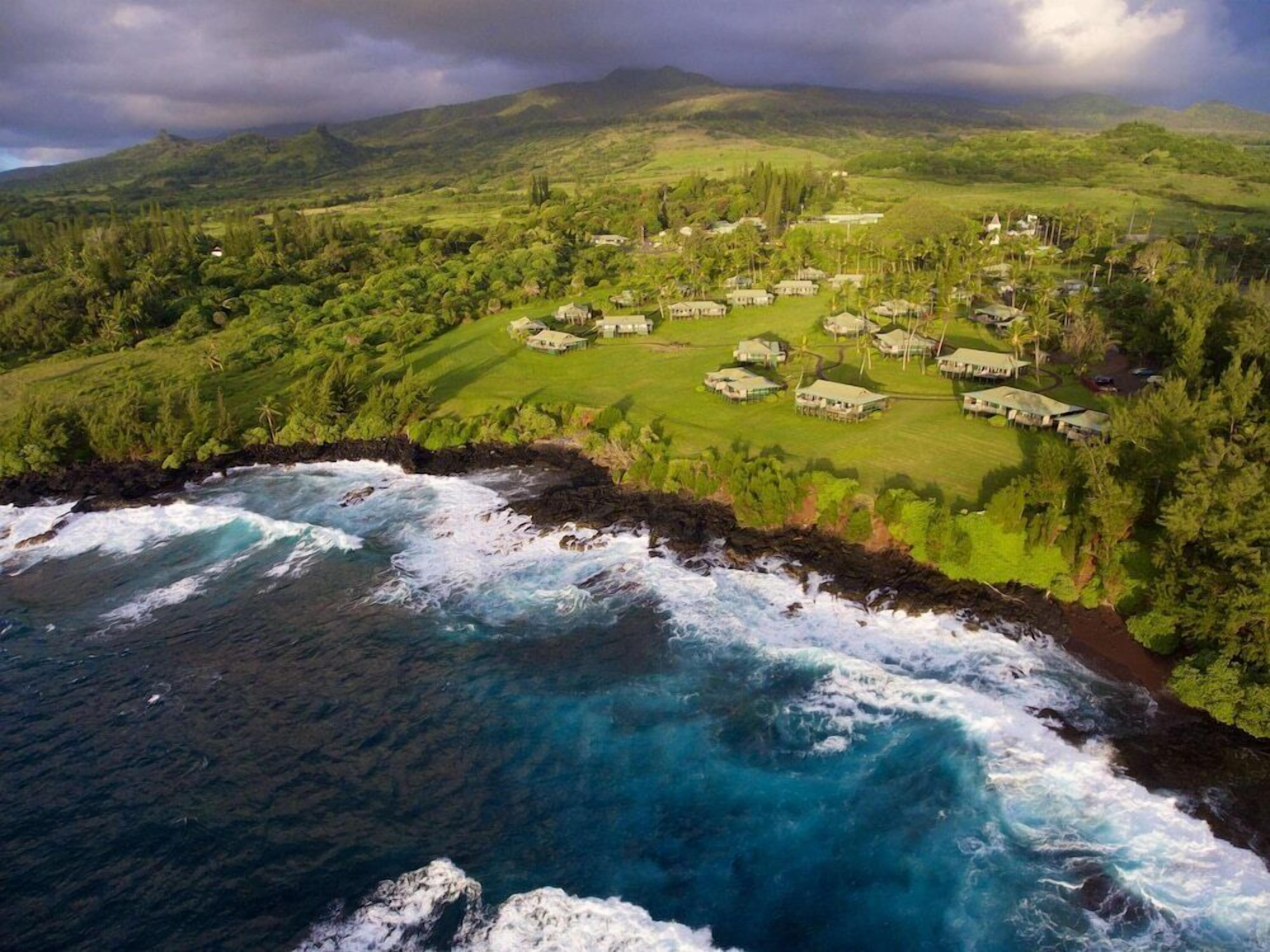 A coastal resort with multiple buildings, a rocky shoreline, and lush greenery.