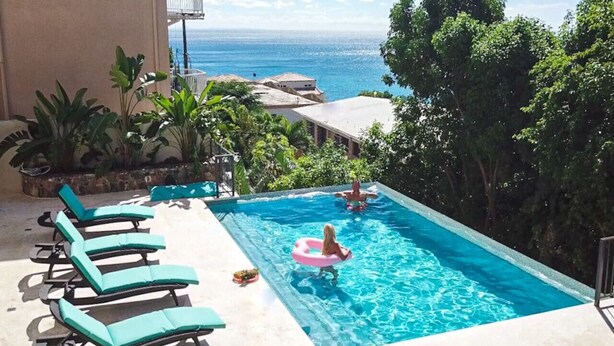 Une piscine avec des chaises longues et vue sur l’océan.