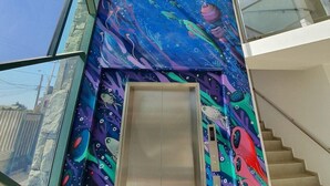 Un bâtiment moderne, orné d’une fresque sous-marine éclatante sur le mur intérieur, doté d’un escalier en verre et offrant une vue dégagée sur l’extérieur.