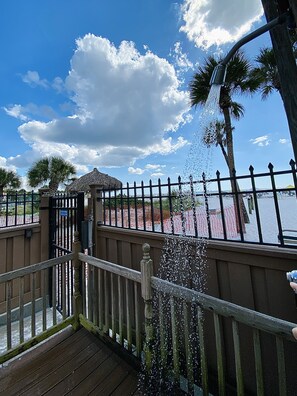 A wooden deck with a railing, a palm tree, and a thatched-roof structure. - PRIVATE BEACH ACCESS. WI-Fi , LOUNGER, PARKING. SIESTA KEY. #1 CRESCENT BEACH. (Sarasota)