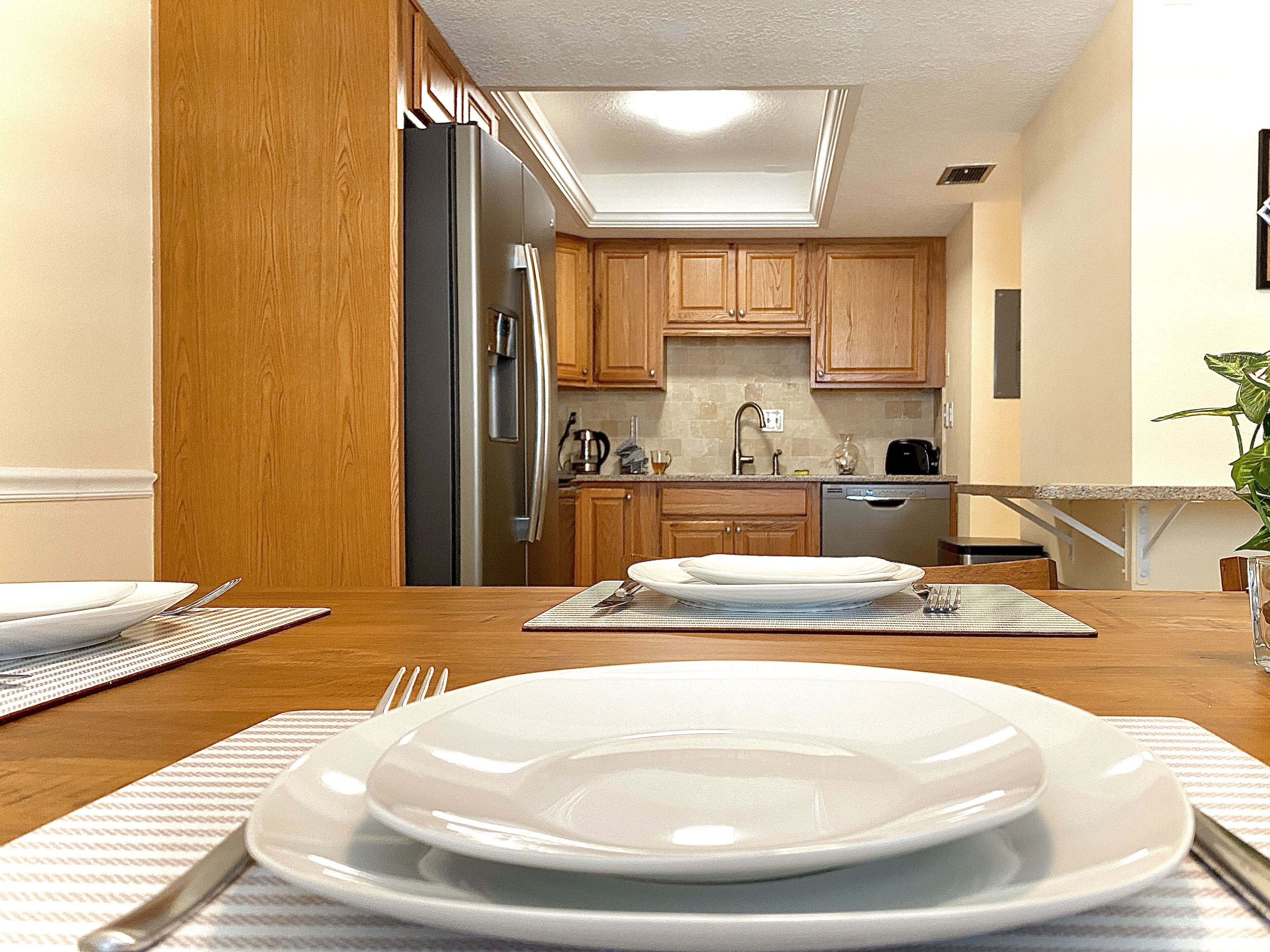 A modern kitchen with wooden cabinets, a stainless steel refrigerator, and a dishwasher.