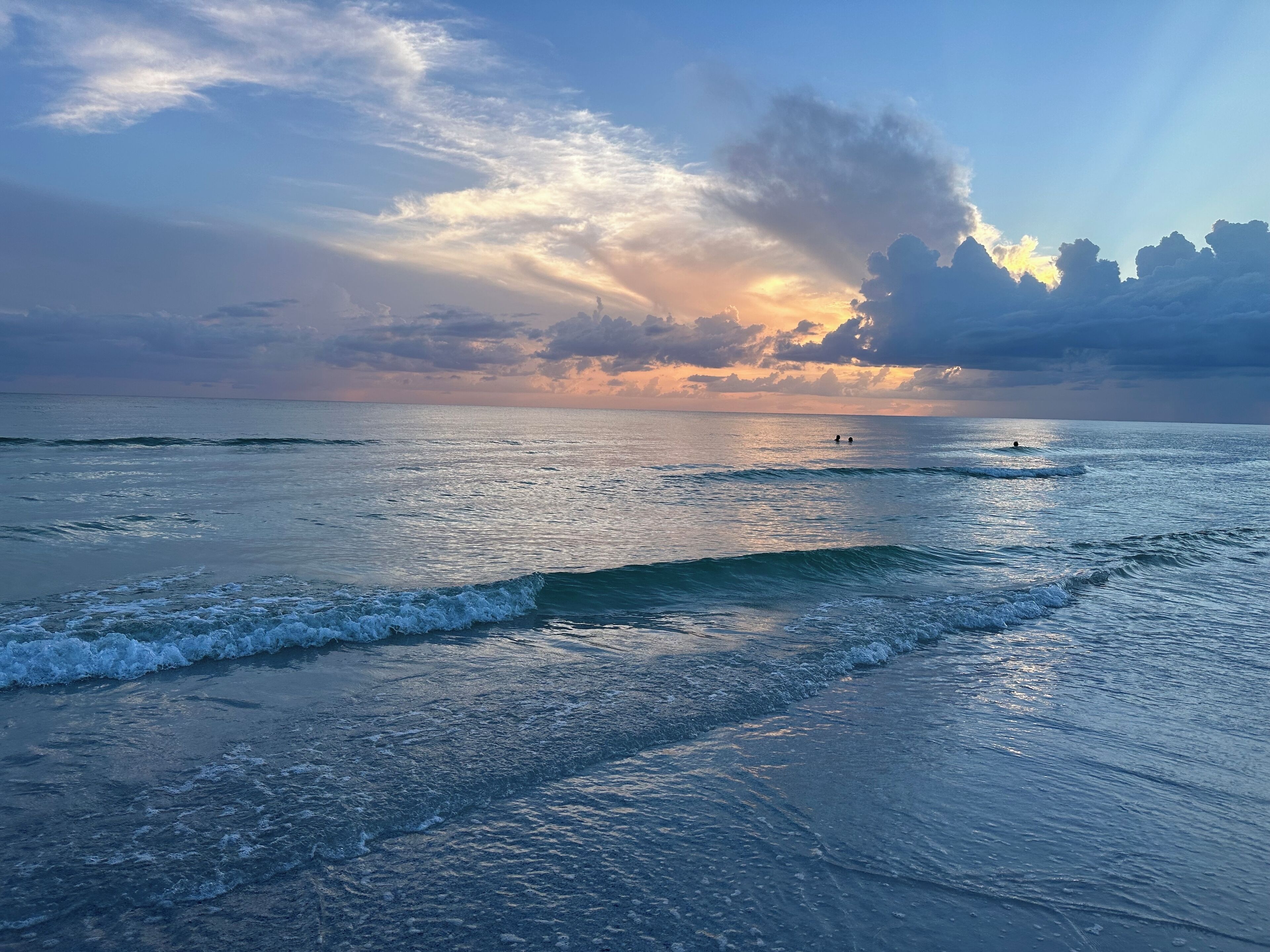 A beach with waves and a sunset.