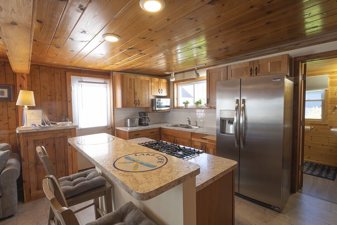 Une cuisine avec des meubles en bois, un réfrigérateur en acier inoxydable, une cuisinière et un plan de travail en granit.
