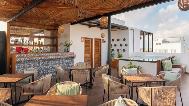 An outdoor seating area with wicker furniture and a bar with bottles.