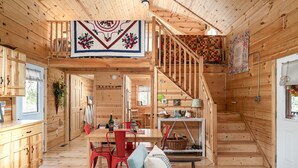 A wooden cabin interior with a dining area, a staircase, and a living room with a sofa and a table. - 2-bedroom vacation home just 10 minutes from Viroqua's charming downtown (Viroqua)