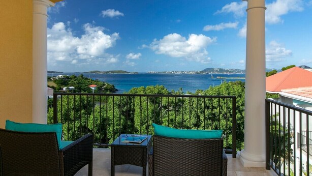 Un balcon doté de meubles en osier et offrant une vue sur la mer.